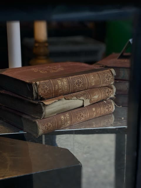 Leather-bound volumes on glass table suggesting narrative depth